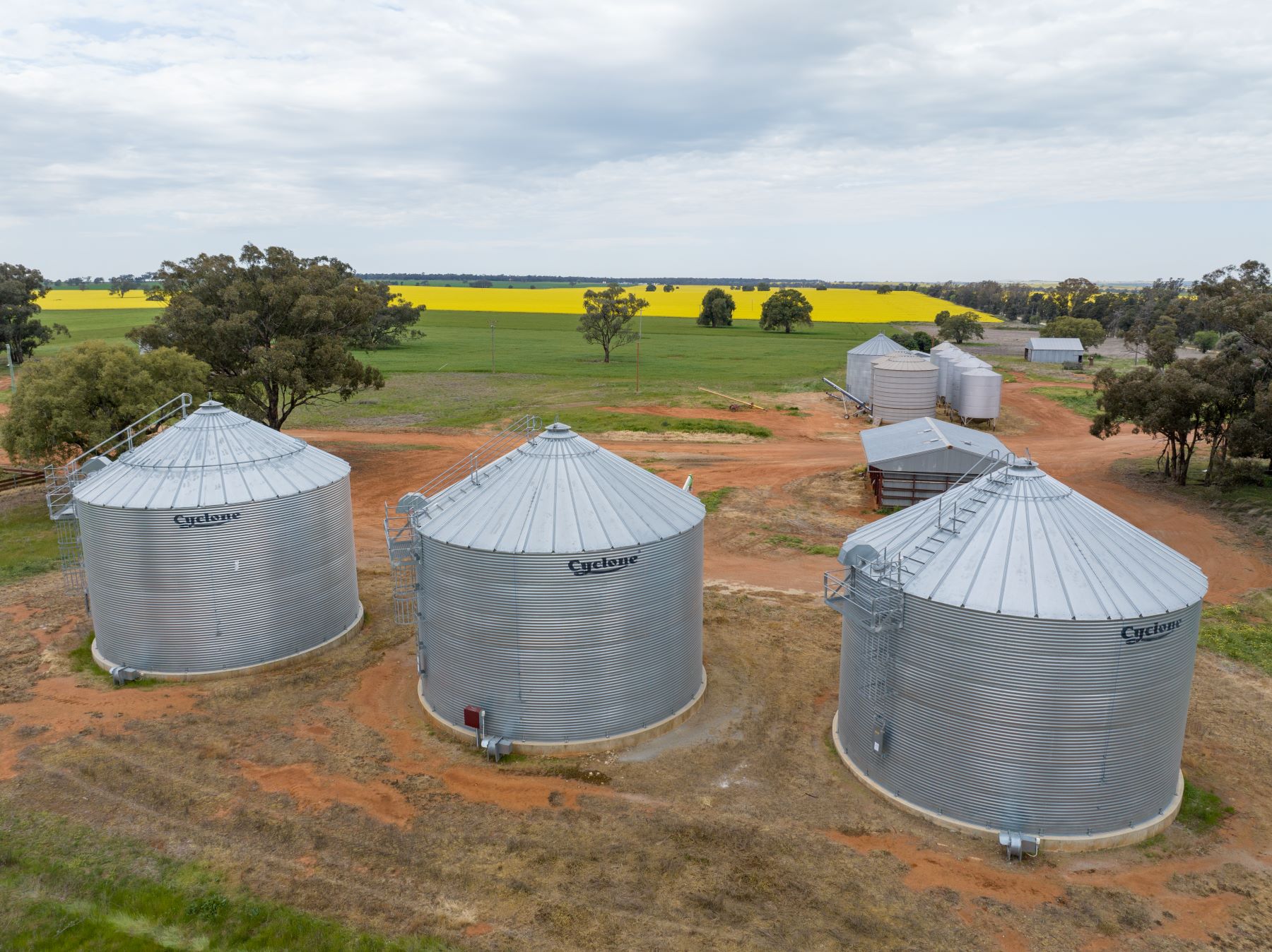Three large silos in front with more sheds and silos in the background