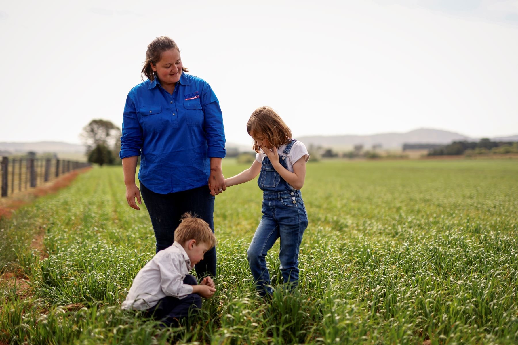 Female farmer and two children in a paddock.